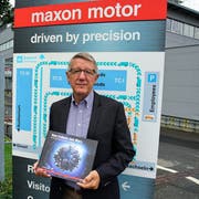 Autor Andreas Anderhalden präsentiert die neue Firmengeschichte vor dem Maxon-Hauptsitz in Sachseln. (Bild: Romano Cuonz (Sachseln, 2. November 2018))