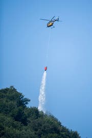 Ein Helikopter löscht den Brandherd nach dem Absturz. (Bild: Urs Flüeler/Keystone (Hergiswil, 4, August 2018))