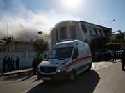 Ein Krankenwagen fährt Verletzte weg. Aus dem Gebäude des Aussenministeriums in Tripolis stieg nach dem Anschlag Rauch auf. (Bild: KEYSTONE/AP/MOHAMED BEN KHALIFA)