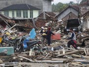 Bewohner suchen in den durch den Tsunami zerstörten Gebäude nach Habseligkeiten. Noch werden viele Menschen vermisst. (Bild: Keystone/EPA/ADI WEDA)