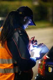 Eine Polizistin kontrolliert einen Fahrzeugausweis. Bild: Stefan Kaiser