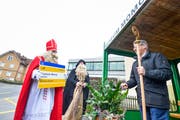 Samichlaus und Schmutzli überreichen das neue Haltestellenschild. (Bild: Donato Caspari)