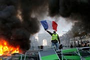 Ein Demonstrant schwenkt die französische Flagge auf der Champs-Elysees. (Bild: AP Photo/Michel Euler, File)
