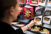Eine Coop-Verkäuferin im Laden bei Canobbio nimmt eine Packung mit Burgern aus Mehlwürmern aus dem Kühlregal (Archivbild). (Bild: Gabriele Putzu/Keystone/TI-Press (Lugano, 21. August 2017))