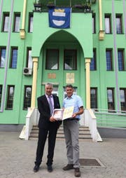 Esad Canic, Präsident des Stadtparlaments von Kalesija (links), überreicht dem ehemaligen Zuger Stadtschreiber Arthur Cantieni vor dem Rathaus von Kalesija die Goldene Plakette. (Bild: PD)
