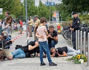 Kampf um das beste Bild: Fotografen machen Bilder von Blumen am Tatort des Münchner Amoklaufs vom 22. Juli. (Bild: AP/Jens Meyer)