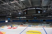 Beim Aufbringen der Werbefolien auf der Eisfläche der Bossard-Arena ist Teamarbeit gefragt. (Bild Maria Schmid)