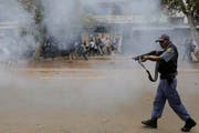 Ein Polizist schiesst mit Gummischrot auf die Demonstranten. (Bild: Kim Ludbrook/EPA (Pretoria, 24. Februar 2017))