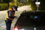 Ein Polizist kontrolliert ein Auto. (Bild Stefan Kaiser)