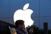 Ein Mann sitzt vor dem Apple-Logo in der Nähe eines Apple-Stores in Beijing, China. (Symbolbild) (Bild: Keystone)