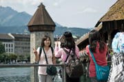 Touristen fotografieren sich vor der Kapellbrücke in Luzern. (Bild Pius Amrein)