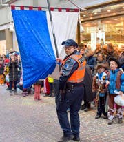 Beim Kinderumzug am Güdisdienstag in der Stadt Luzern springt ein Polizist als Fahnenträger ein. (Bild: Leserbild Walter Linke)