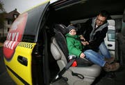 Taxifahrer Daniel Krummenacher von Mc Taxi Luzern montiert den Kindersitz seines Sohnes Rian (3 Jahre) in seinem Taxi. (Bild Chris Iseli/Neue LZ)