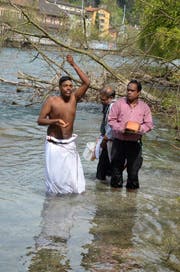 Der Sohn des Verstorbenen (links) bespritzt sich mit Wasser, nachdem er die Asche seines Vaters der Reuss übergeben hat. (Bild Benno Bühlmann)