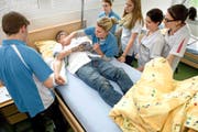 Ein angehender Fachmann Gesundheit (links) entnimmt unter Instruktionen der Ausbildnerin und unter den Augen seiner Kolleginnen eine Blutprobe. (Bild Nadia Schärli)
