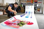 Lars Fricker von Fuchs-Design AG begutachtet ein Dominique-Gisin-Plakat. (Bild: Corinne Glanzmann / Neue OZ)
