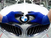 Ein Angestellter bringt bei einem BMW das Marken-Logo an (Archiv) (Bild: Keystone)