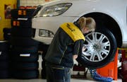 Eine Frau putzt in einer Garage die Felgen. (Bild: Keystone / Urs Flüeler)
