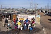 Bewohner der Langa Township in der Nähe von Kapstadt holen Wasser bei einer Sammelstelle. (Bild: MARTIN RUETSCHI (KEYSTONE))