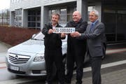 Gestellte Übergabe des Autokennzeichens mit der Nummer ZG 100001 (von links): Reto Krebs, Unternehmer in Cham, Fahrer des Firmenwagens sowie Markus Feer, Leiter des Strassenverkehrsamts. (Bild PD)