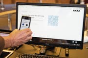 Stadtpräsident Dolfi Müller scannt den QR-Code zur Registrierung seiner digitalen Identität. (Bild: Alexandra Wey/Keystone (Zug, 15. November 2017))
