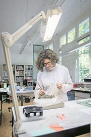Restauratorin Petra Nirmaier befreit bronzene Beschläge eines römischen Holzkästchens aus einem Erdblock. (Bild: Pius Amrein (Sursee, 18. Juli 2017))