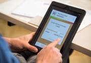 Ein Mann hält ein Tablet mit einer App zur Überprüfung von Fake News in den Händen. (Bild: Silas Stein / EPA)