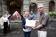 Yvonne Ruckli, Präsidentin der Jungfreisinnigen, übergibt Stadtschreiber Toni Göpfert die Unterschriften für den Erhalt der Kapellbrücke-Giebelbilder-Kopien. (Bild: Manuela Jans / Neue LZ)