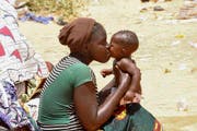 Die Frau ist Flüchtling aus Nigeria küsst ihr Kind in einem Transit-Camp. (Bild: EPA / STR)