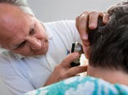 Ein Arzt untersucht eine Patientin. (Bild: Martin Ruetschi / Keystone)