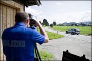 Ein Polizist misst die Geschwindigkeit vorbeifahrender Autos (Symbolbild). (Bild: Keystone)