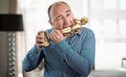 Komiker Sergio Sardella (45) beisst in seinem Wohnzimmer auf den Swiss Comedy Award. (Bild: Corinne Glanzmann (Emmenbrücke, 16. März 2017))
