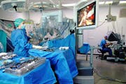 Arzt Agostino Mattei (rechts) bedient den Roboter. Links im Bild beobachtet die Operationsassistentin am Bildschirm, was er macht. Bild: Nadia Schärli (Luzern, 11. Oktober 2016)