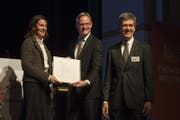 Der Zuger Volkswirtschaftsdirektor Matthias Michel (Mitte) übergibt den Preis an Annette Luther (CEO Roche Diagnostics) und Christoph Löffler von Roche Diagnostics. (Bild: Maria Schmid (Cham, 10.November 2016))
