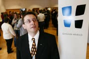 Hitzkirchs Gemeindepräsident Serge Karrer posiert neben dem Wappen der Gemeinde Hitzkirch, während die Anwesenden beim Apéro auf die Fusion anstossen. Bild Philipp Schmidli / Neue LZ