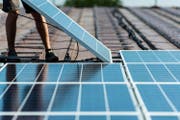 Auf einem Dach werden Solarmodule montiert. (Bild: Christian Beutler/Keystone)