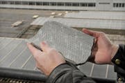 Ein Bruchstück einer der Eternitplatten, die vom Bahnhofdach fielen. Im Hintergrund sieht man Stapel der Platten auf dem Dach. (Bild Pius Amrein/Neue LZ)