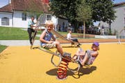 Tom und Enya Buholzer spielen auf dem neuen Spielplatz Kapelle in Meggen. Im Hintergrund der Gemeindeammann HansPeter Hürlimann (links) und Projektleiter Tobias Widrig. (Bild: PD)