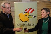 Schulratsvizepräsident Alexander Imhof und Schulratspräsidentin Ruth Regli stossen an, im Hintergrund das Logo. (Bild Urs Hanhart/Neue UZ)