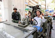 Gelöste Stimmung in Bangkok trotz Ausrufung des Kriegsrechts: Ein marokkanischer Tourist posiert für ein Erinnerungsfoto in einem Armeefahrzeug der thailändischen Armee. (Bild: Keystone)