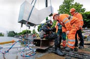 Die Skulptur «Seesicht» des Künstlers Roman Signer wurde am Dienstag am Zuger Vorstadtufer zu Wasser gelassen. Taucher Miklos Erismann (links) verschraubte und verzurrte das Kunstwerk mit Fenster. (Bild: Stefan Kaiser / Neue ZZ)