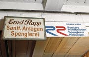 Das Firmenschild des Gründers Ernst Rapp und ein neueres an der Decke der Werkstatt. (Bild: Werner Schelbert (13. Dezember 2017))