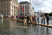 Hochwasserschäden nehmen gemäss der Gebäudeversicherung Luzern zu. Im Bild ist zu sehen, wie Einwohner und Gäste in Luzern nach dem Hochwasser von 2005 über einen Steg den Schwanenplatz passieren. (Archivbild / Keystone / Sigi Tischler)