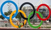 Nicht im Dienst: Eine freiwillige Helferin macht es sich in Rio auf einem olympischen Ring bequem. (Bild: EPA/Sergei Ilnitsky)