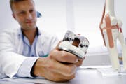 Reto Twerenbold, leitender Arzt der orthopädischen Chirurgie des Zuger Kantonsspitals, zeigt ein künstliches Kniegelenk. Das Modell eines Knies ist am rechten Bildrand zu erkennen. (Bild Werner Schelbert)