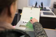 Eine Frau wirft das Wahlcouvert in die Urne (gestellte Szene). (Bild: Roger Grütter/Neue LZ)