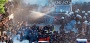 Ein Polizist richtet einen Wasserwerfer gegen Demonstrierende am Rande des G20-Gipfels. Bei den Protesten ist es gestern zu heftigen Krawallen gekommen. (Bild: Michael Probst/Keystone (Hamburg, 6. Juli 2017))