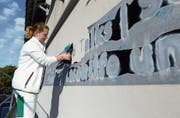 Die Malerin Andrea Brändli entfernt die Folie, hinter der verschiedene Begriffspaare erscheinen.
