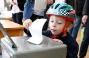 Noe Bouissoux aus Bern wirft den Abstimmungszettel seines Vaters in die Wahlurne. (Bild: Keystone / Peter Klaunzer)