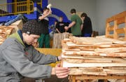 Schüler Tobias Omlin schichtet die Schindeln aufeinander. (Bild Corinne Glanzmann/Neue OZ)